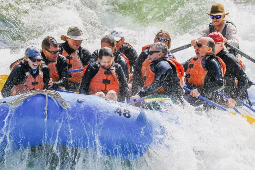 Group of men and women splashed during white water rafting