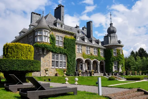 Stone building with trimmed hedges and gravel pathways