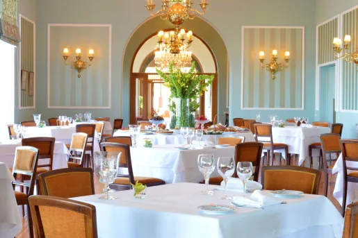 Dining room with tables with wine glasses and brown chairs