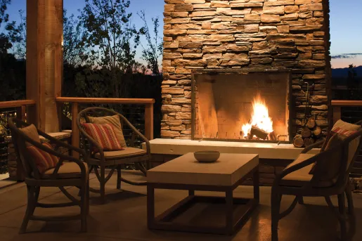 Four chairs in an outdoor patio in front of a stone fire place
