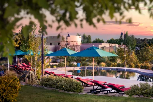 Outdoor pool with blue umbrellas and red chairs
