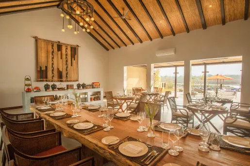 Indoor dining area with long, wooden tables, plates and glasses of wine on the tables