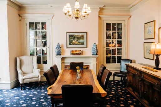 Indoor seating area with a wooden table and leather chairs, with painting on the walls