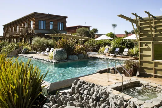 Outdoor pool in front of a wooden hotel building