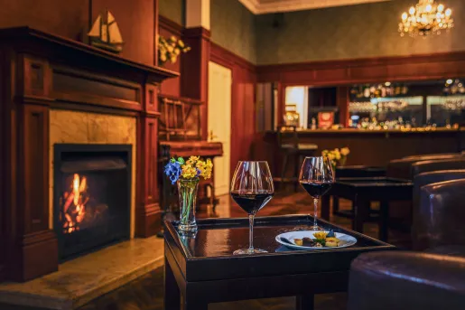 Table with two wine glasses in front of a fireplace in an indoor lounge