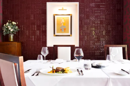 Dining table in a red room, with glasses of wine and a plate of food on the table