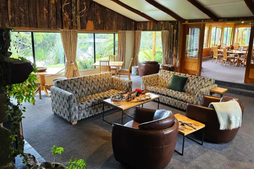 Large room in a wooden lodge with cushioned sofas and a dining table in the back