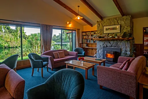Seating area with red and green sofas and a stone fireplace in the center