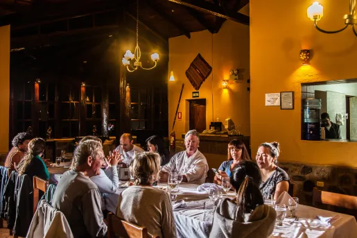 Group of people sitting at a long, rectangular dining table sipping on glasses of wine