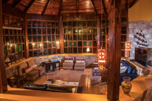 Indoor view of wooden lodge wit an open seating area, and dangling red light fixtures