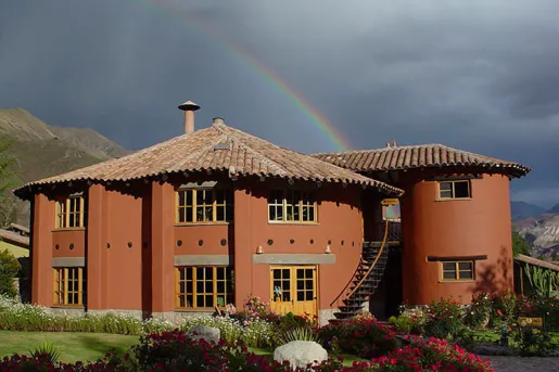 red house in front of a rainbow in the sky
