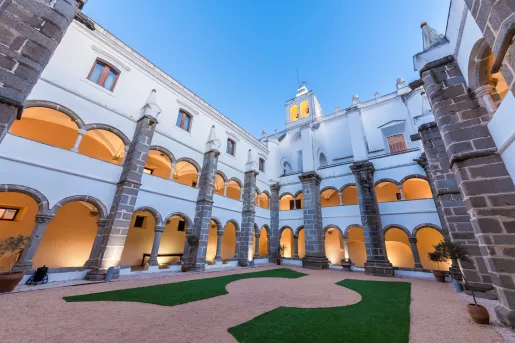 Exterior view of white hotel building with balconies that have large archways