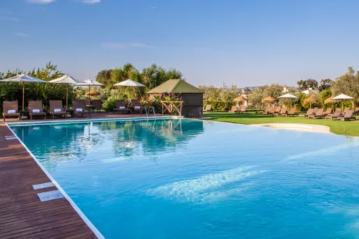 Outdoor swimming pool surrounded by a wooden plank walkway and wooden reclining chairs