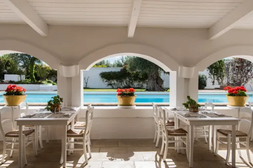 Outdoor dining area with white archways, and flowers sitting on top of each table