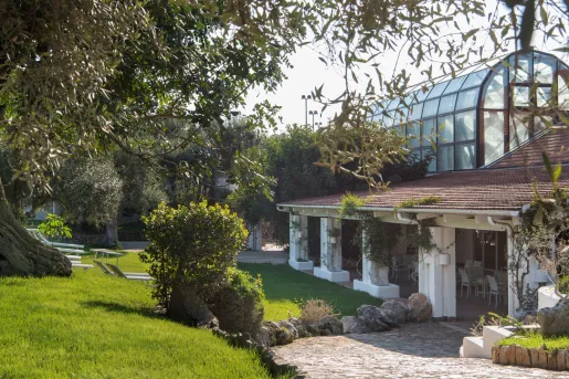 Exterior view of building with a greenhouse on the top floor, with a garden in front
