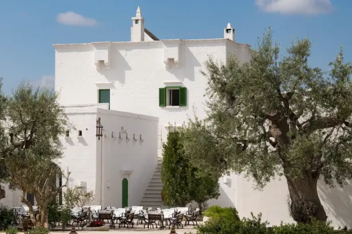 White buildings with green accents, with an outdoor courtyard surrounded by trees