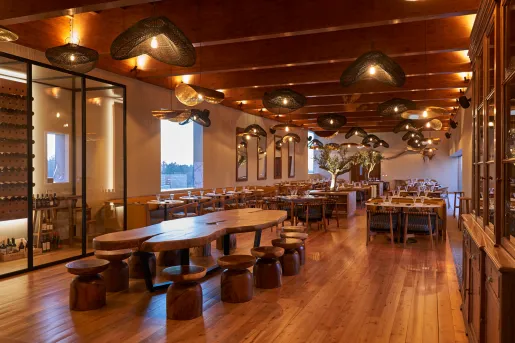 Indoor dining area with a large wooden table in the center and a wine cellar to the left