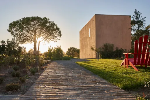 Outdoor stone walkway with a red chair on the right and a tall tree to the left