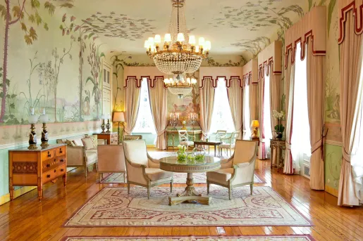 Room with large curtains, flower wallpapers, and green and white furniture on hardwood floors