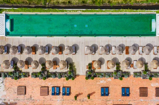 Sky view of outdoor pool with umbrellas and chairs on one side