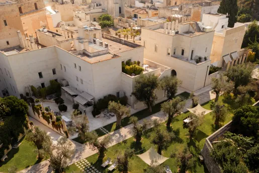 Top view of white buildings surrounded by trees and outdoor tables