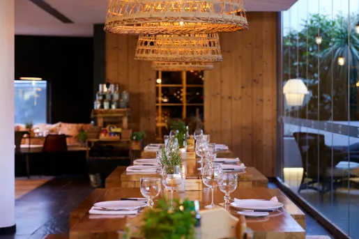 Wooden tables with wine glasses and woven ceiling light fixtures