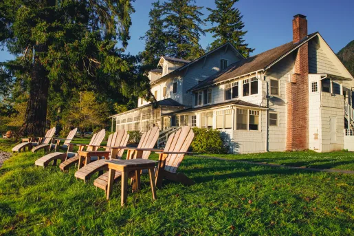 White house with a red chimney and six brown lawn chairs outside