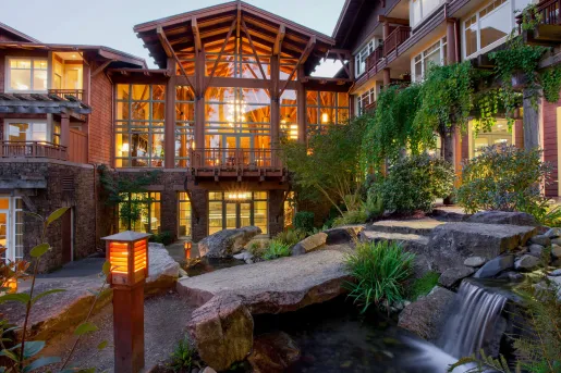 Wooden building with large windows and a mini, outdoor waterfall made of rocks