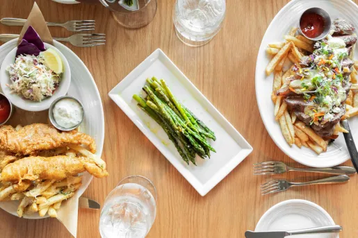 Plates of asparagus, fish and chips, and fries