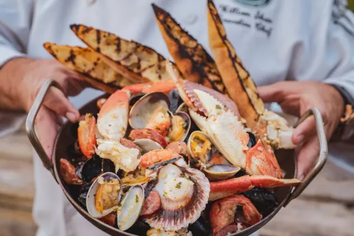Person holding up a plate full of seafood with 4 slices of charred bread