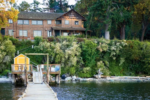 Exterior view of a wooden lodge building above, with a lake and bridge under