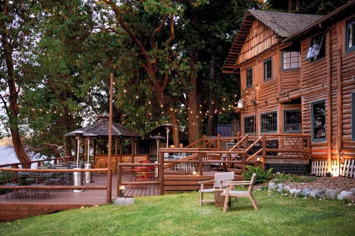 Exterior view of cabin-style building with a wooden patio and string lights