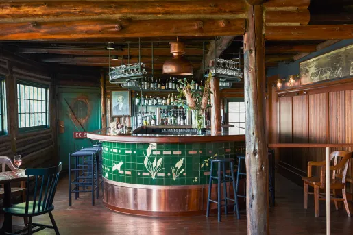 Indoor bar counter surrounded by blue stools, with wooden pillars around the room