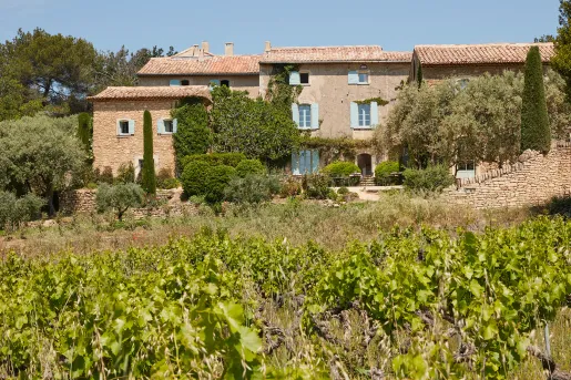 Red-brick building with green crops and trees in front