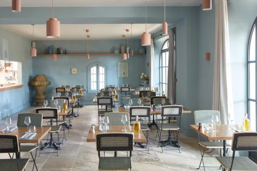 Indoor dining area with wooden chairs and tables, with bottles of alcohol on each table