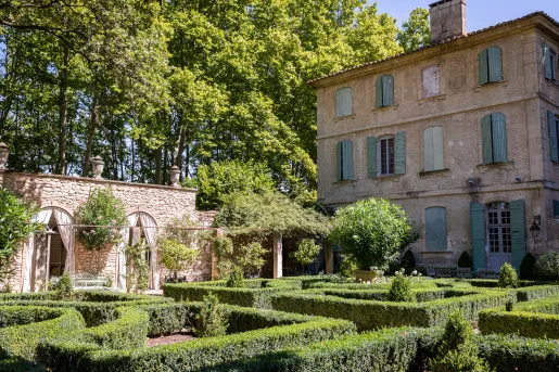 Outdoor garden with trimmed bushed next to a stone building