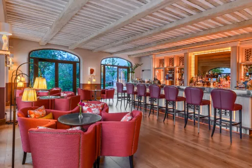 Bar and lounge filled with red cushioned chairs and stools