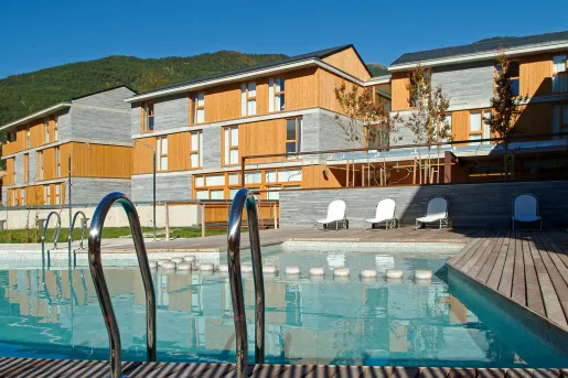 Outdoor pool next to a wood and stone hotel building