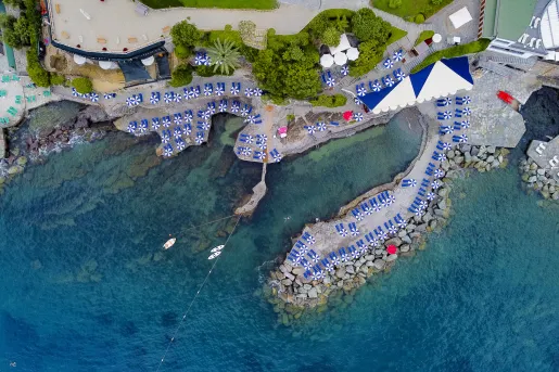 Sky view of a port with blue chairs and umbrellas next to the water