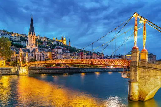 Illuminated suspension bridge leading to a rustic town