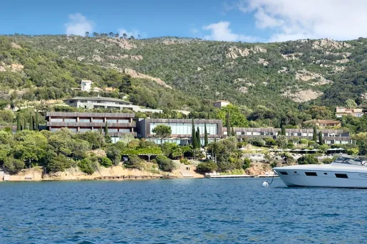 External view of gray building with a yacht in the ocean in front