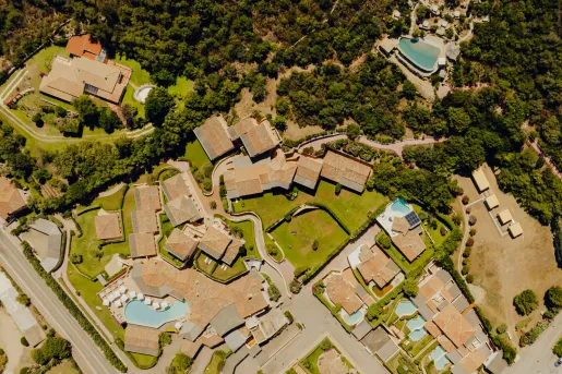 Sky view of tan colored buildings, surrounded by trees and minim outdoor pools