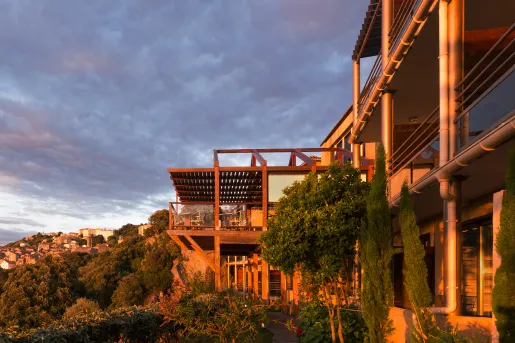 Exterior view of metal and wooden building, surrounded by trees in the sunset