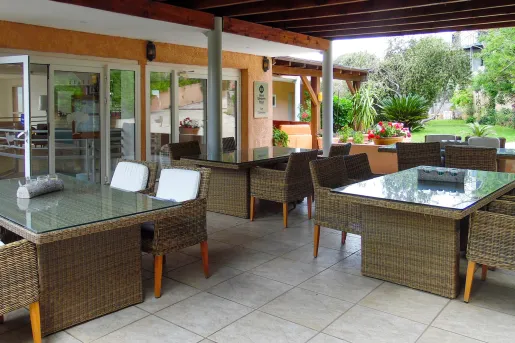 Ourdoor dining area with woven chairs and tables, under an outdoor patio