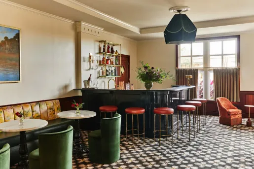Indoor bar and lounge, with green cushioned chairs and red bar stools