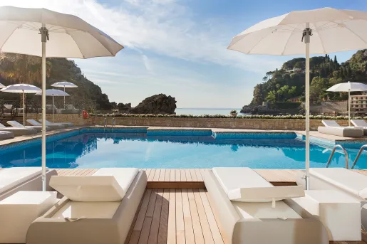 Outdoor pool with large, white umbrellas and white reclining chairs