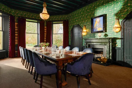 large dining room table next to fireplace in wallpapered room