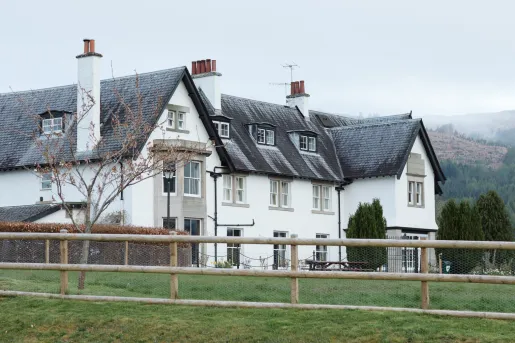 White cottage-style building with a black roof and an open grass area in front