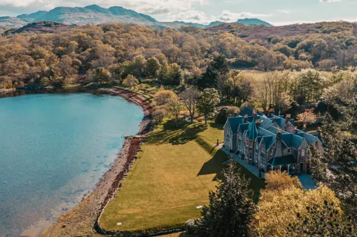 Castle-like building with an open grass area next to a lake