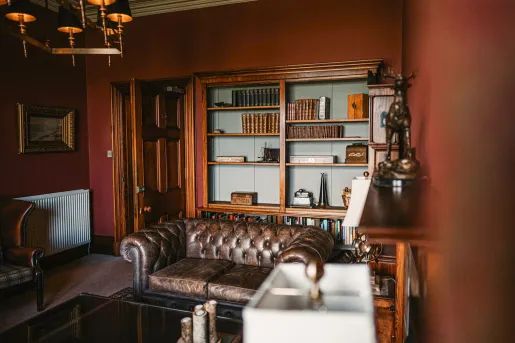 Leather couch in a library room with antiques on the wall